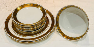 A selection of fine bone china made in England by Shelley.  The plates have a white base colour and are decorated with a band on gold filigreee.  The set includes cake plates, saucers, a tea bowl  and a side plate.  